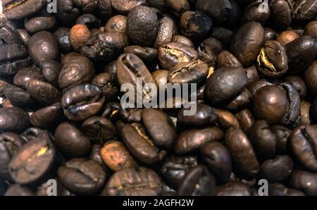 Grande gruppo di materie Roasted Brown i chicchi di caffè immagazzinato in un contenitore e quindi la massa. Sfocate e profondità di campo. Vista ravvicinata. L'agricoltura un Foto Stock