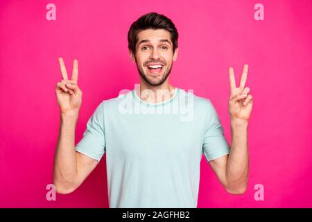 Foto di divertenti macho guy mostra v-simbolo segno di dire ciao a migliori amici indossare t-shirt casual isolato rosa vibrante colore di sfondo Foto Stock