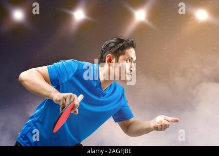 Tabella asiatici giocatore di tennis uomo che serve la sfera con faretti sfondo Foto Stock