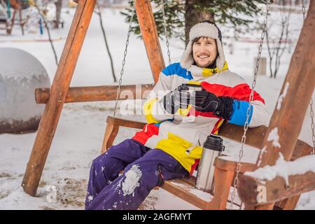 Snowboarder bevande tè da un thermos in corrispondenza di una stazione sciistica Foto Stock