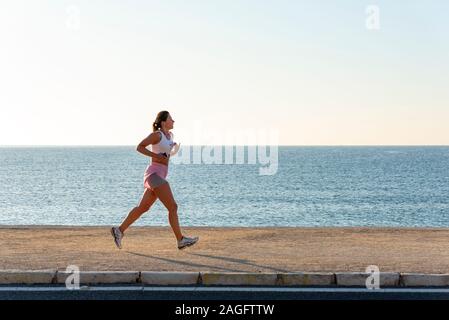 Donna jogging in spiaggia con un telefono, Alicante, Spagna Foto Stock