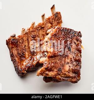 Due appiccicosa piccante grigliate di porzioni delle nervature di un barbecue su uno sfondo bianco in stretta fino a menu pubblicità Foto Stock