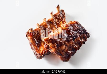 Deliziosa piccante alla griglia marinati nervature in due porzioni di fresco da un barbecue disposti su uno sfondo bianco per la pubblicità Foto Stock