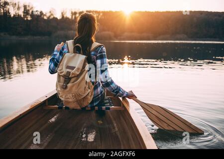 Vista posteriore della donna in canoa sul lago al tramonto Foto Stock