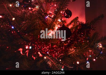 Red Globe appeso sull'albero di natale circondato da luci Foto Stock