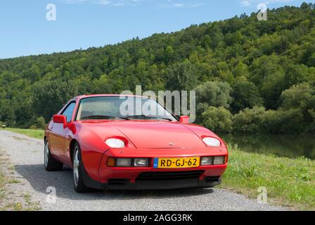 Olandese rosso vintage Porsche 928 S parcheggiato lungo il fiume Main in Germania Foto Stock