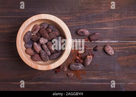 Le fave di cacao nella ciotola sul tavolo di legno Foto Stock