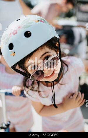 Bambino con casco di sicurezza di sbirciare da dietro gli occhiali da sole Foto Stock