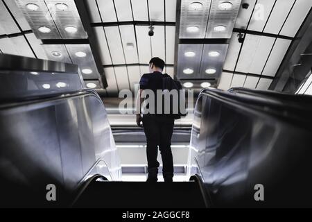 Uomo turistico salendo sulle scale di Escalator. Foto Stock