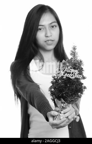 Studio shot di giovani asiatici ragazza adolescente dando felice anno nuovo albero con focus sulla struttura ad albero Foto Stock