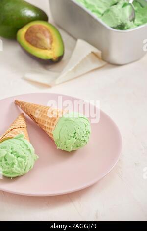 Verde avocado gelato scoop in coni wafle su sfondo bianco. Spazio di copia Foto Stock