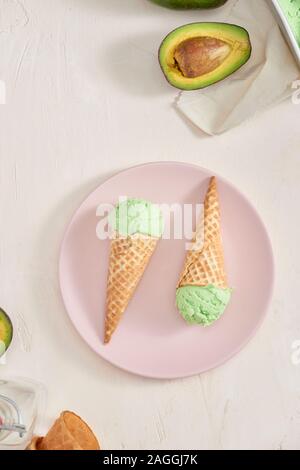 Verde avocado gelato scoop in coni wafle su sfondo bianco. Spazio di copia Foto Stock