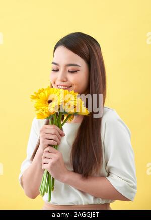 Giovane donna odore di girasoli su sfondo giallo Foto Stock