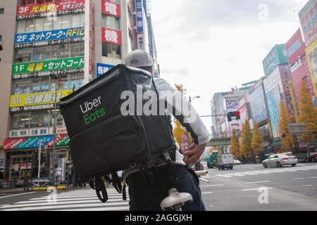 Tokyo, Giappone. Xviii Dicembre, 2019. Un Uber mangia ciclista passeggiate attraverso Chuo-dori Avenue cross road a Akihabara, Tokyo.Akihabara, chiamato anche Akiba dopo un ex santuario locale, è un quartiere centrale di Tokyo che è famosa per i suoi molti negozi di elettronica. In anni più recenti, Akihabara ha guadagnato il riconoscimento come il centro del Giappone otaku (i cultori del ventilatore) cultura e molti negozi e stabilimenti dedicati alle anime e manga ora sono dispersi tra i negozi di elettronica nel distretto. Credito: Stanislav Kogiku SOPA/images/ZUMA filo/Alamy Live News Foto Stock