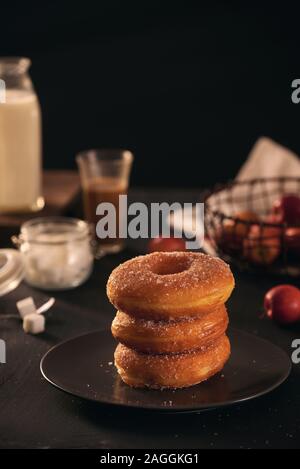 Ciambelle fresche con lo zucchero in polvere e il caffè con il latte su un tavolo di legno. La prima colazione nel villaggio. Foto Stock