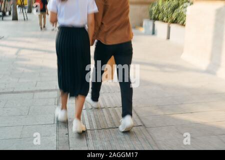 Abbassare la sezione corpo di un giovane turista giovane a piedi da store windows e tenendo la carta shopping bags in una città di destinazione. Foto Stock