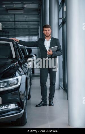 Lunghezza completa foto. Moderno ed elegante imprenditore barbuto nel salone automobilistico Foto Stock