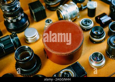 Closeup retrò mockup, rotonda in pelle scatola vintage in centro e vintage accessori fotografici e quipments intorno su sfondo di legno. Foto Stock