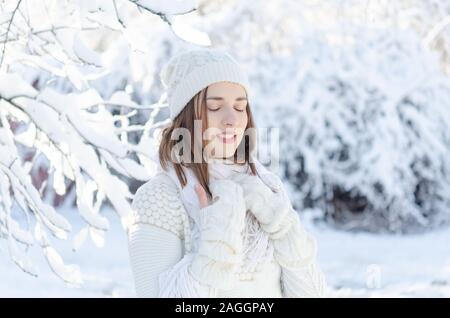 Ragazza caucasica indossa un maglione bianco e guanti in una fredda giornata invernale. Ella gode di una bella giornata d'inverno. Foto Stock