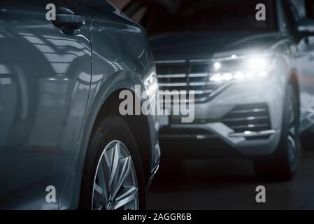 In camera oscura. Vista delle particelle delle moderne macchine di lusso parcheggiate al chiuso in ore diurne Foto Stock