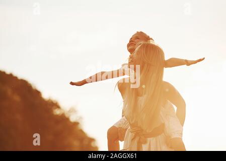 Immaginate di volare. Madre e figlia godendo di fine settimana insieme a piedi all'aperto nel campo. La bellissima natura Foto Stock