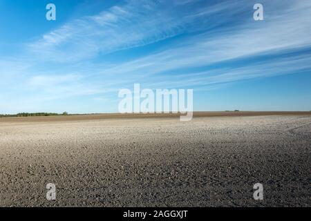 Grande campo arato e nuvole bianche su un cielo blu Foto Stock