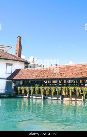 Il vecchio ponte in legno sul turchese del fiume Aare nella storica città di Thun in Svizzera. Costruzione del ponte è decorata con tradizionali fiori alpini. Punto di riferimento turistici. Fotografia verticale. Foto Stock