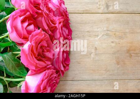 Il giorno di San Valentino sfondo con le rose rosa su un tavolo di legno. Vista dall'alto. Selective soft focus. Copia di testo spazio. Compleanno, giorno di nozze concept Foto Stock