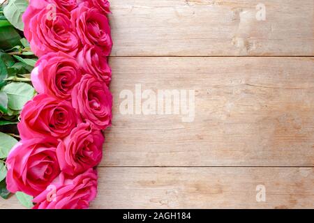 Il giorno di San Valentino sfondo con le rose rosa su un tavolo di legno. Vista dall'alto. Selective soft focus. Copia di testo spazio. Compleanno, giorno di nozze concept Foto Stock