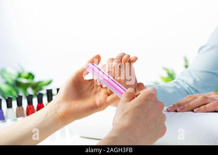 Manicurist utilizzando lima per unghie e creare forma pulita Foto Stock