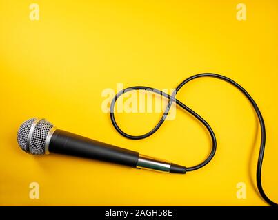 Microfono con cavo arricciato su sfondo giallo Foto Stock