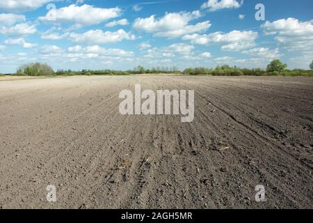 Appena campo arato, nuvole bianche sul cielo blu - soleggiata giornata di primavera Foto Stock