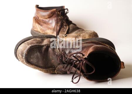 Fotografia di uomo di Dirty old stivali in pelle su sfondo bianco Foto Stock