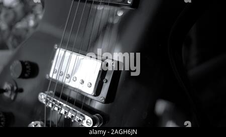 Primo piano in scala di grigi delle corde di una chitarra Foto Stock