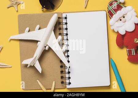 Aeroplano giocattolo su un blocco note con copia spazio. Un concetto sul tema della pianificazione delle vacanze per il fine settimana di Natale Foto Stock