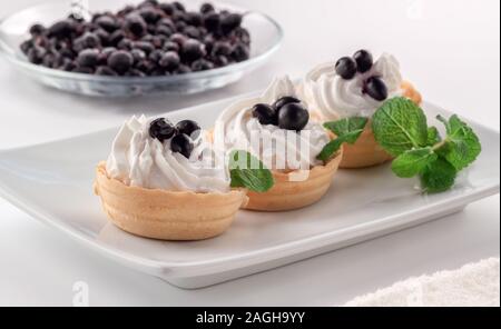 Pasticcini fatti in casa con crema di formaggio e frutti di bosco freschi - uve secche di Corinto e le foglie di menta Foto Stock