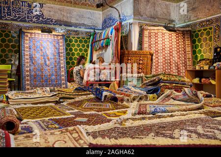 La tessitura dei tappeti le donne all'interno Sher-Dor Madrasah, famoso Registan di Samarcanda, Uzbekistan in Asia centrale Foto Stock