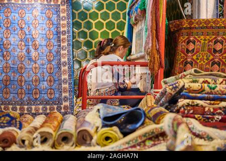 La tessitura dei tappeti le donne all'interno Sher-Dor Madrasah, famoso Registan di Samarcanda, Uzbekistan in Asia centrale Foto Stock