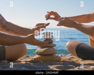 Paio di costruire una piramide di pietra sulla spiaggia. Le relazioni di amore e di concetto. Foto Stock