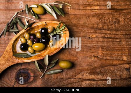 Sulla tavola in legno rustico, una ciotola con vari tipi di olive Foto Stock