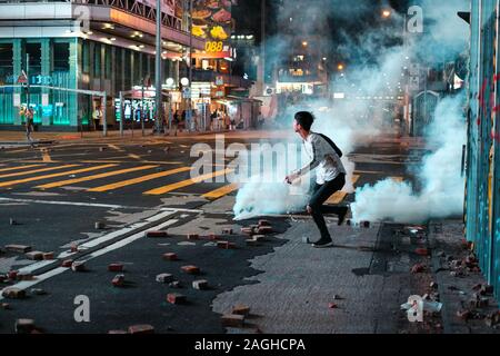 HongKong - Novembre 2019: il giovane uomo che corre dal gas lacrimogeni durante il 2019 HongKong proteste Foto Stock