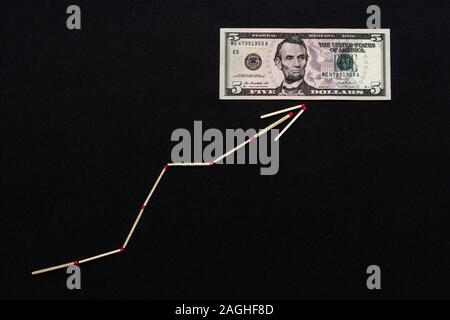 Il bianco matchstick freccia mostra il dollaro che sorge su uno sfondo nero. Foto Stock