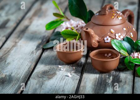 Il tè in piccolo marrone yixing teiera e la primavera sbocciano i fiori sul vecchio sfondo di legno Foto Stock