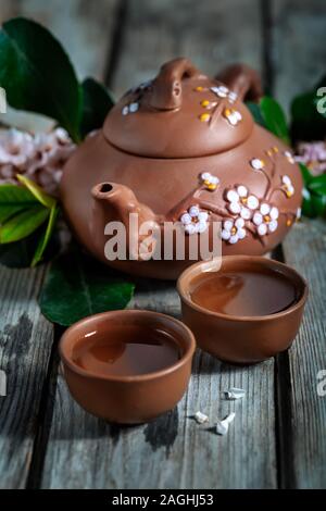 Il tè in piccolo marrone yixing teiera e la primavera sbocciano i fiori sul vecchio sfondo di legno Foto Stock