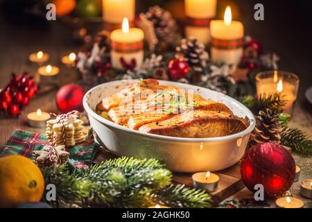 Cena di Natale da pescare il salmone nel piatto di torrefazione con decorazione di festa corona di Avvento e candele. Foto Stock