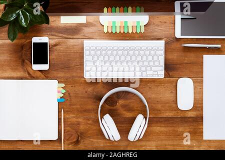 Tech tavolo moderno con vuoto vuoto organizer portatile con la penna per i lavori di pianificazione e il monitor di un computer sulla scrivania con dispositivi auricolari sulla tastiera Foto Stock