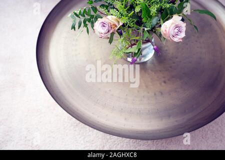 Vassoio in argento con rose viola in vaso su un tavolo contro il tappeto di lusso vista superiore, bella decorazione interno Foto Stock