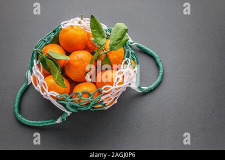 Tangerini in una rete mesh shopping bag. Rifiuti Zero e nessuna busta di plastica del concetto. Spazio di copia Foto Stock