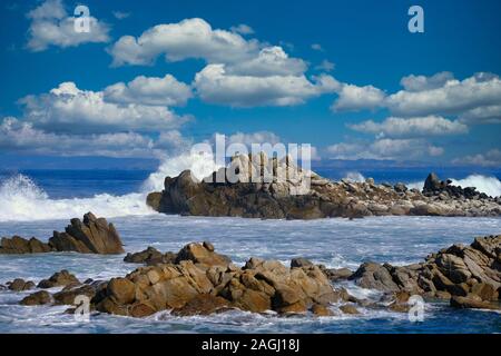 Surf che si infrangono sulle rocce Foto Stock