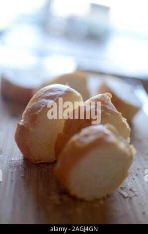 Close up di strati di carta bianca comune e nuova francese baguette di pane sul tagliere di legno Foto Stock